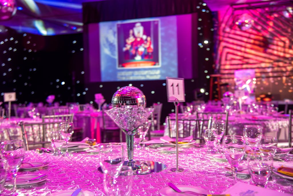 Lavish themed dinner setup with disco balls and purple lighting for a glamorous event.