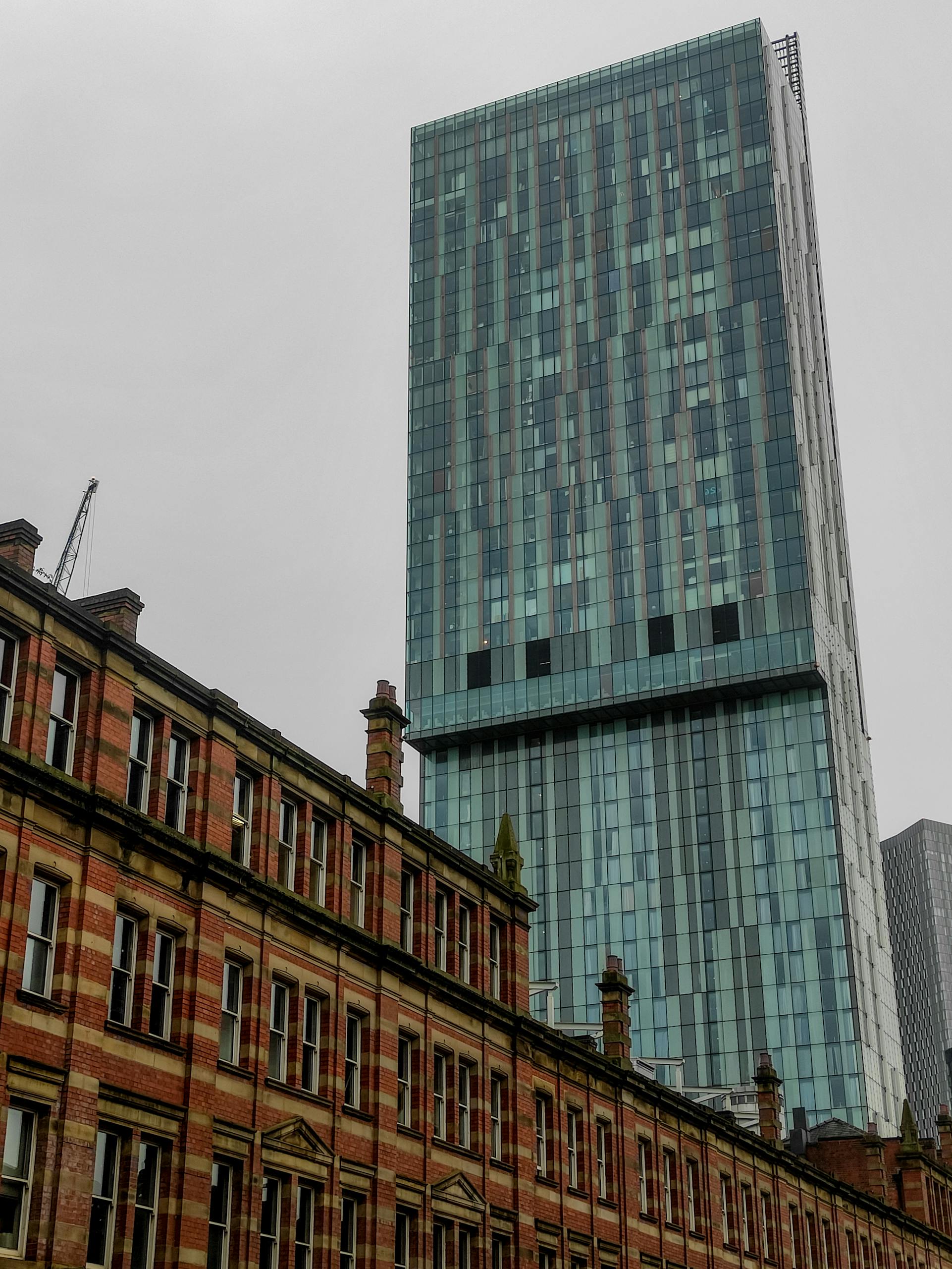 This vertical shot captures the contrast between modern skyscrapers and historic buildings in Manchester, England.